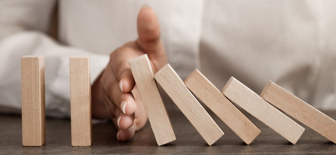 hand stops falling wooden domino blocks, risk insurance concept,